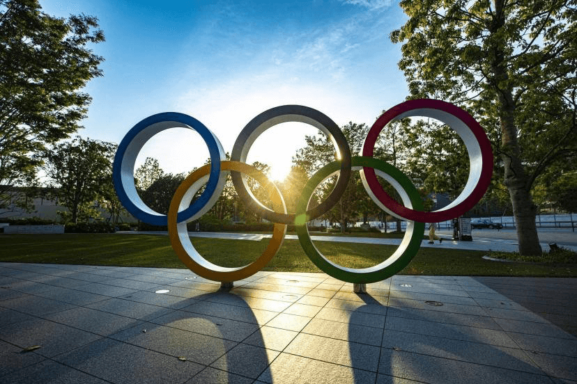 Statue of the Olympic Games logo under a sunset
